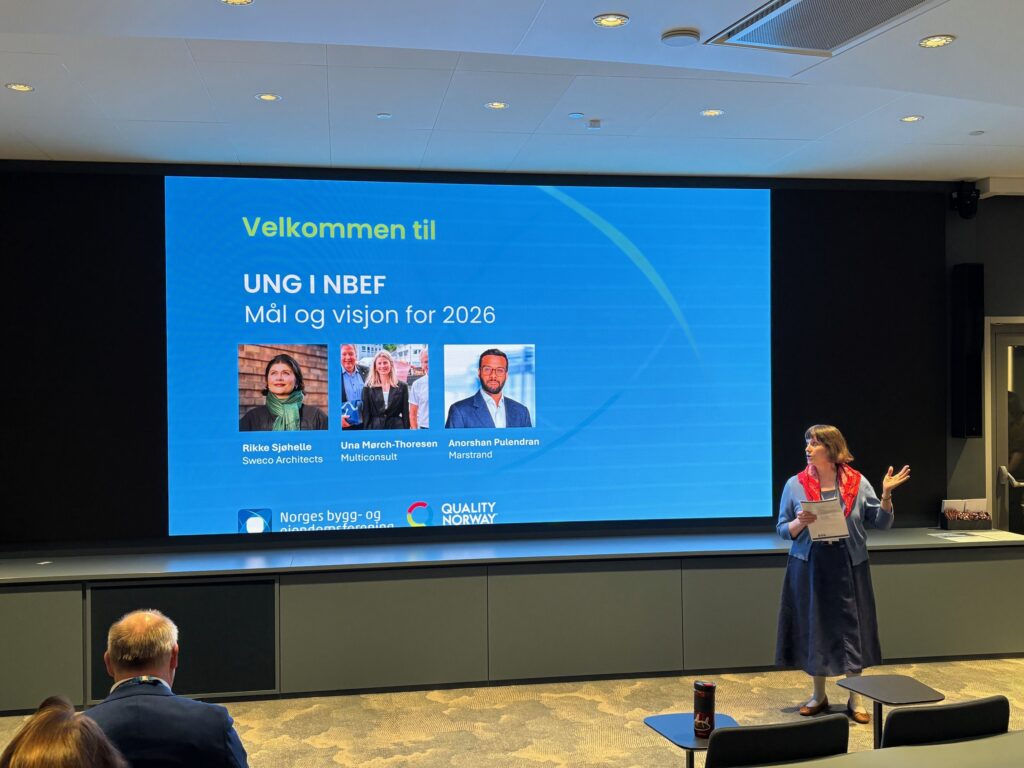 Conference stage with a large blue welcome slide reading 'Velkommen til' and 'UNG I NBF Mål og visjon for 2026', showing four panelist headshots at the bottom and a presenter on the right side.
